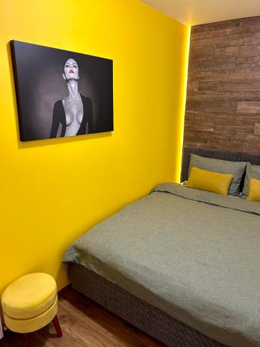a yellow bedroom with a bed and a picture of a woman at Happy Home in Târgu-Mureş