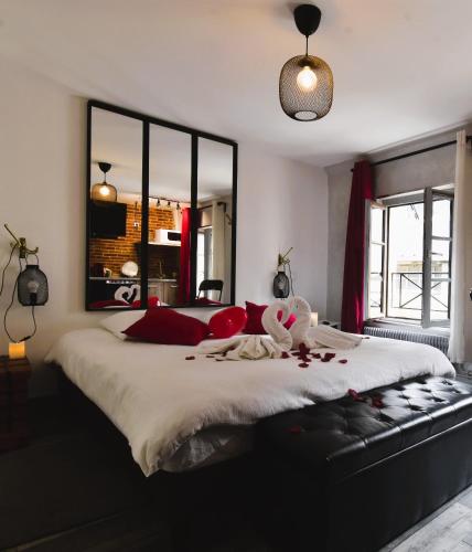 une chambre avec un grand lit avec des oreillers rouges dans l'établissement Appartement jacuzzi privatif : Urban Love, à Verneuil-sur-Avre