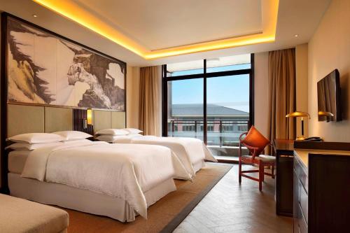 una camera d'albergo con tre letti e una grande finestra di Four Points by Sheraton Chengdu, Anren a Dayi
