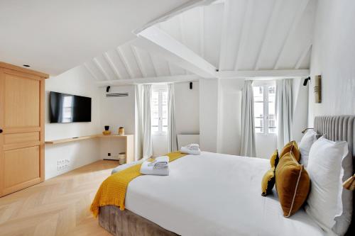 une chambre avec un grand lit blanc et une télévision dans l'établissement Pick A Flat's Apartement in Saint-Germain-des-Prés - Rue de Seine, à Paris