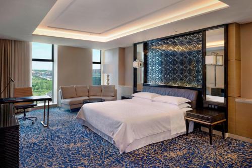 長春市にあるシェラトン チャンチュン ジンユェタン ホテルのベッドとデスクが備わるホテルルームです。