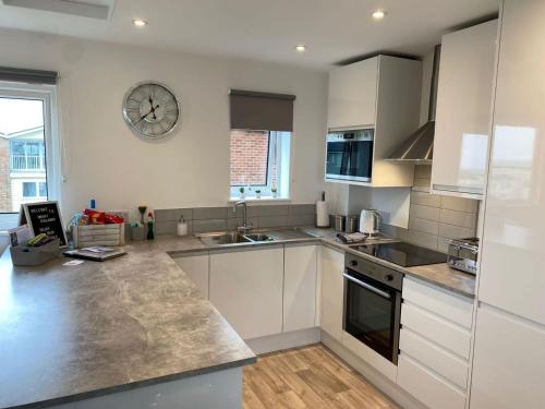 a kitchen with white cabinets and a clock on the wall at Hunny Hideaway, Hunstanton - dog friendly haven by the sea in Hunstanton