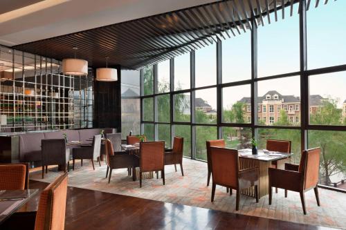 a restaurant with tables and chairs and large windows at Sheraton Changchun Jingyuetan Hotel in Changchun