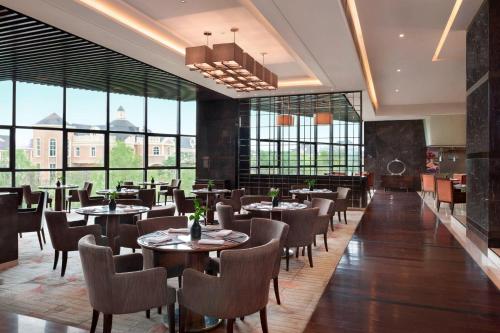 a restaurant with tables and chairs and large windows at Sheraton Changchun Jingyuetan Hotel in Changchun