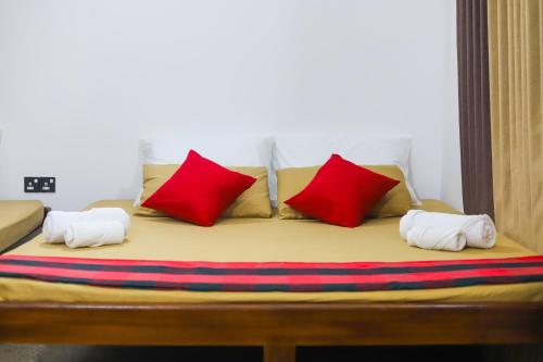 Una cama con almohadas rojas y blancas. en Royal Hub en Negombo