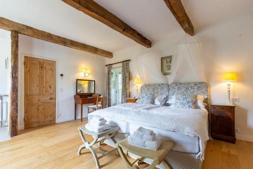 ein Schlafzimmer mit einem großen Bett und einem Schreibtisch in der Unterkunft Le Moulin sur Célé - Luxury Villa with Private Pool in Saint-Sulpice