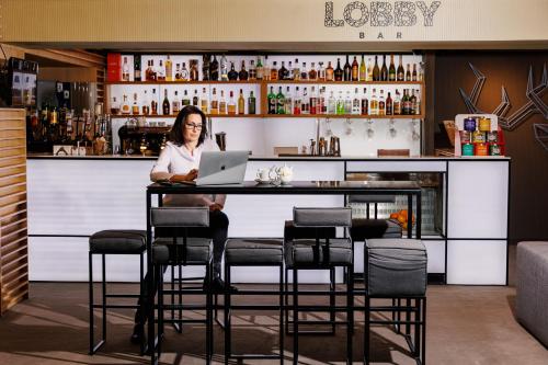a woman sitting at a bar with a laptop at Lucky Bansko Aparthotel SPA & Relax in Bansko