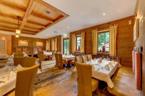 a restaurant with white tables and chairs and wooden walls at ROBINSON AMADÉ in Kleinarl
