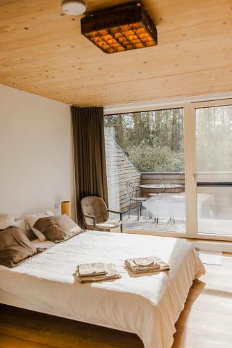 a bedroom with a large bed and a large window at ScraB&Ble Ecologische gastenkamers in Bornem