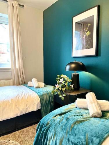 a blue room with two beds and a table with a lamp at Damson Drive- Boutique Home in Oldbury