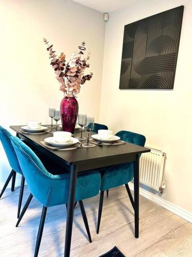 a table with chairs and a vase with flowers on it at Damson Drive- Boutique Home in Oldbury