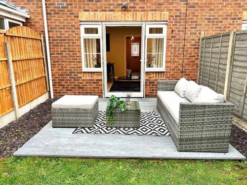 a patio with two wicker chairs and a table at Damson Drive- Boutique Home in Oldbury