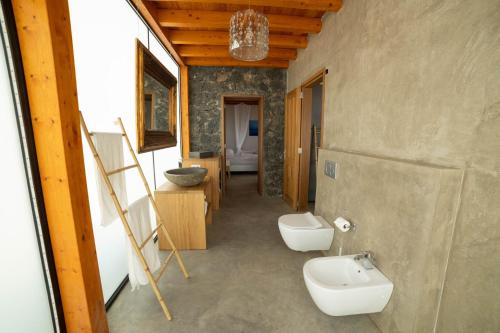 uma casa de banho com 2 WC, um lavatório e um espelho. em Casa Julie em Chilegua