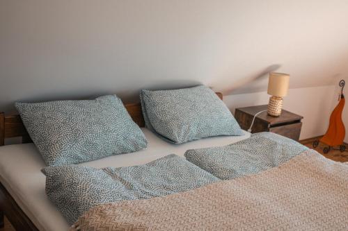 a bed with two pillows and a table with a guitar at Remete Vendégház in Szekszárd