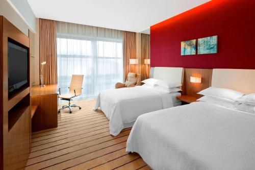 um quarto de hotel com duas camas e uma televisão de ecrã plano em Four Points by Sheraton Qingdao, Chengyang em Qingdao