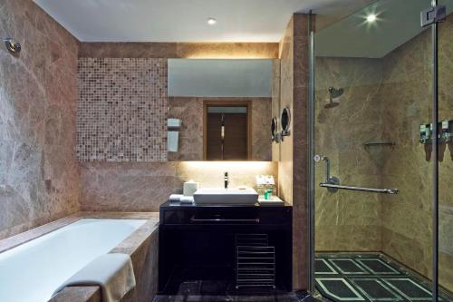 uma casa de banho com uma banheira, um lavatório e um chuveiro em Four Points by Sheraton Qingdao, Chengyang em Qingdao