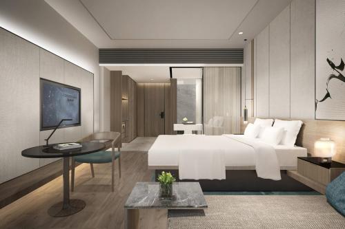 Un dormitorio con una gran cama blanca y una mesa en Courtyard by Marriott Pinghu, en Pinghu