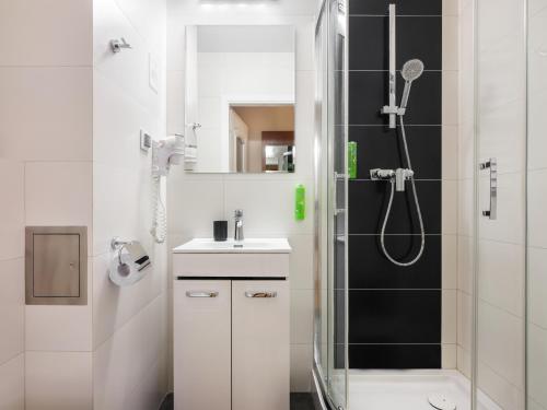 baño blanco con ducha y lavamanos en Kosmopolita Rooms en Cracovia
