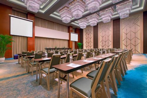 a conference room with tables and chairs and a projection screen at The Westin Qingdao - Instagrammable in Qingdao