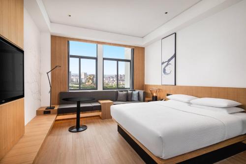 a bedroom with a bed and a couch and a television at Fairfield by Marriott Jingzhou in Jingzhou