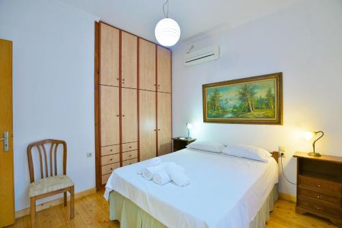 a bedroom with a white bed and a chair at Drossos Garden House in Nydri