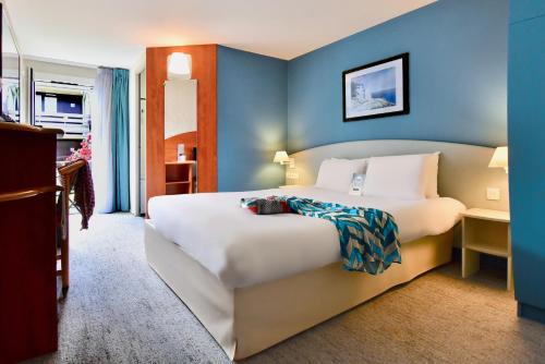 een slaapkamer met een groot wit bed en een blauwe muur bij Kyriad Lannion-Perros-Guirec in Lannion