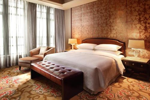 JiangyinにあるSheraton Jiangyin Hotelの大きなベッドと椅子が備わるホテルルームです。