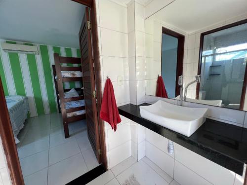 a bathroom with a white sink and a mirror at casa de praia com piscina para famílias in Ipioca
