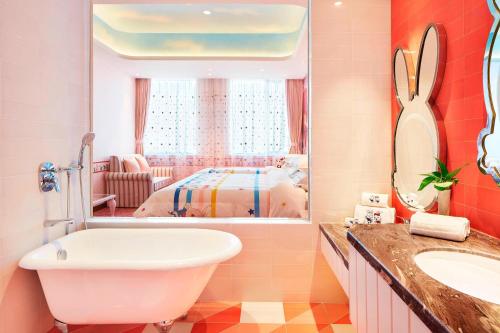 Sheraton Harbin Xiangfang Hotel في هاربين: حمام مع حوض ومغسلة وغرفة نوم