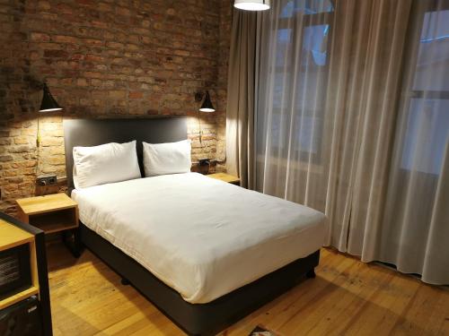 a bedroom with a large bed with a brick wall at Novus Pera Hotel in Istanbul