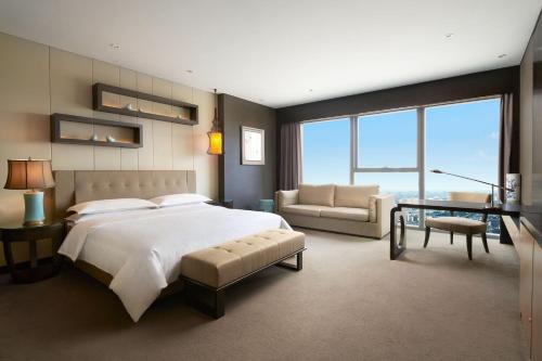 sypialnia z dużym łóżkiem i salonem w obiekcie Sheraton Shanghai Waigaoqiao Hotel w Szanghaju