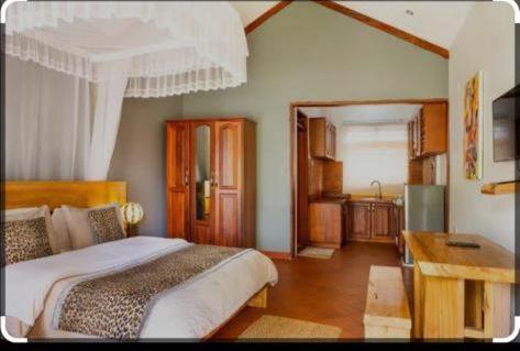 a bedroom with a large bed and a wooden desk at KIZUNGU FOREST COTTAGES & SPA in Kampala