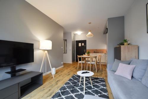 a living room with a blue couch and a table at RentPlanet - Apartamenty Koło Brzegu in Kołobrzeg