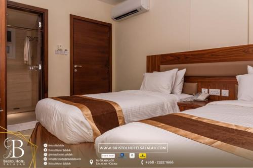 a hotel room with two beds and a bathroom at Bristol Hotel Salalah in Salalah