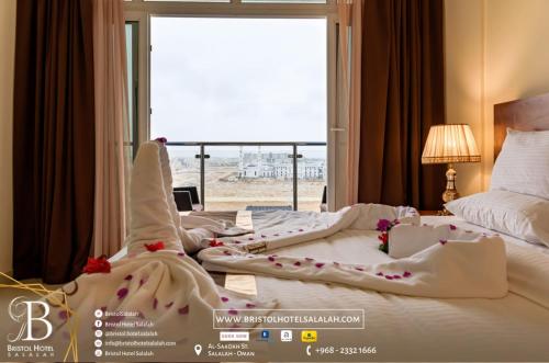 a hotel room with two beds and a large window at Bristol Hotel Salalah in Salalah