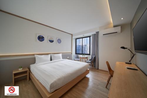 a bedroom with a white bed and a desk and a table at Prom Hotel in Bangkok