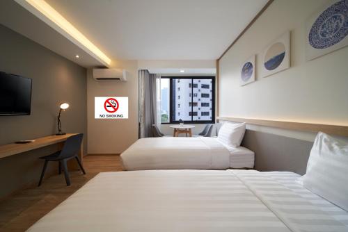 a hotel room with two beds and a desk and a television at Prom Hotel in Bangkok