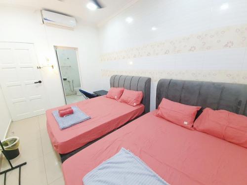 2 Betten in einem Zimmer mit roten Kissen in der Unterkunft Lot 90 Seremban Town Homestay in Seremban