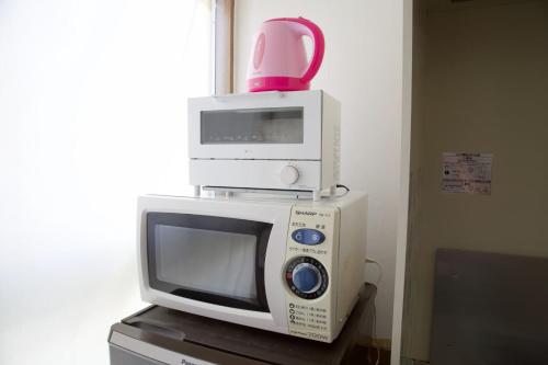a microwave with a pink pot on top of it at ピースリー安里 501 in Tomari