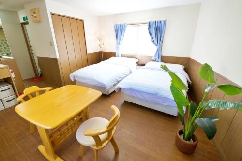 a bedroom with two beds and a table and a table and chairs at ピースリー安里 501 in Tomari