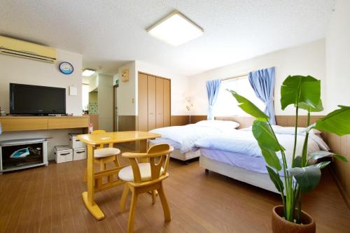 a hotel room with two beds and a table and a tv at ピースリー安里 501 in Tomari