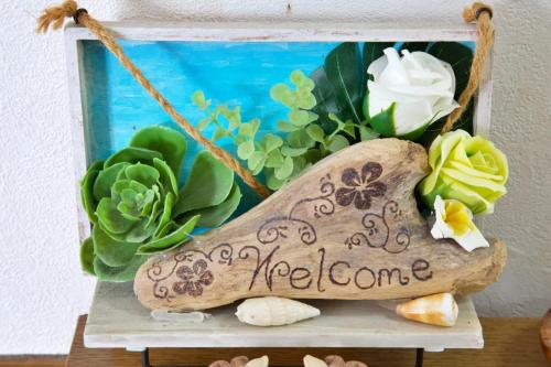a welcome sign sitting on a shelf with flowers at ピースリー安里 501 in Tomari