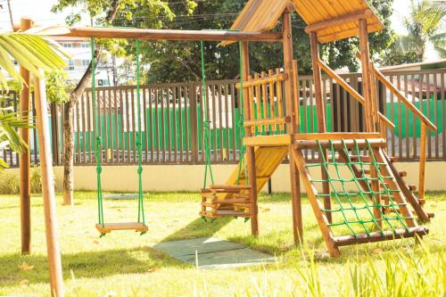 a playground with a wooden swing set in a yard at Green Porto 204 - Flat novo no centro de Porto de Galinhas in Porto De Galinhas
