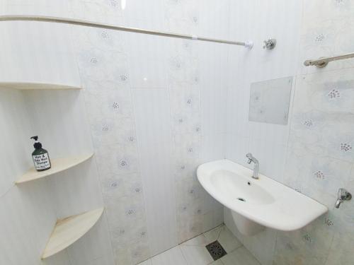 ein weißes Badezimmer mit einem Waschbecken und einem Spiegel in der Unterkunft Lot 90 Seremban Town Homestay in Seremban