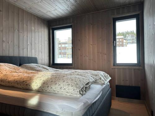 a bedroom with a bed and two windows at Hafjell - Penthouse - ski in/out in Hafjell