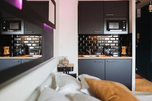 uma cozinha com armários pretos e um lavatório num quarto em LovRoz em Perros-Guirec