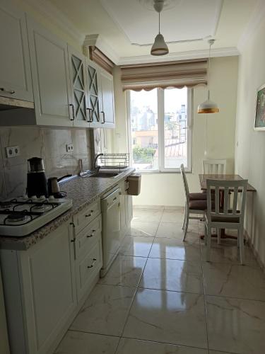 uma cozinha com armários brancos, uma mesa e uma janela em Heart of The City + History + Amenities + City Attractions em Antalya