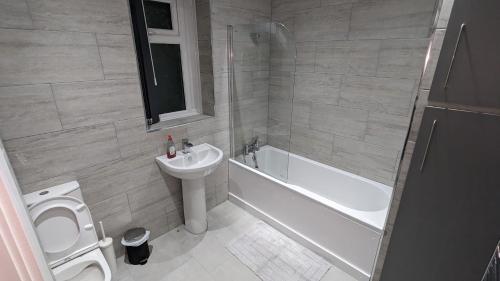 a bathroom with a sink and a toilet and a tub at Modern 4 Bedroom House, Hollin Hill Ave in Roundhay
