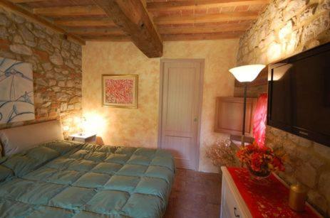 a bedroom with a bed and a flat screen tv at Agriturismo San Ansanino- Piscina con spiaggia-Aria condizionata in Pari