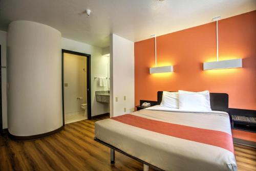 a bedroom with a large bed with an orange wall at Motel 6-Bozeman, MT in Bozeman